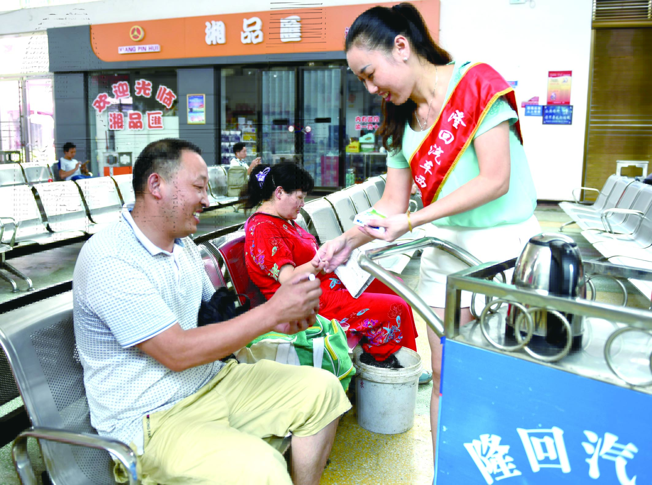 隆回分公司汽車西站工作人員正在為旅客免費(fèi)贈送藿香正氣水。