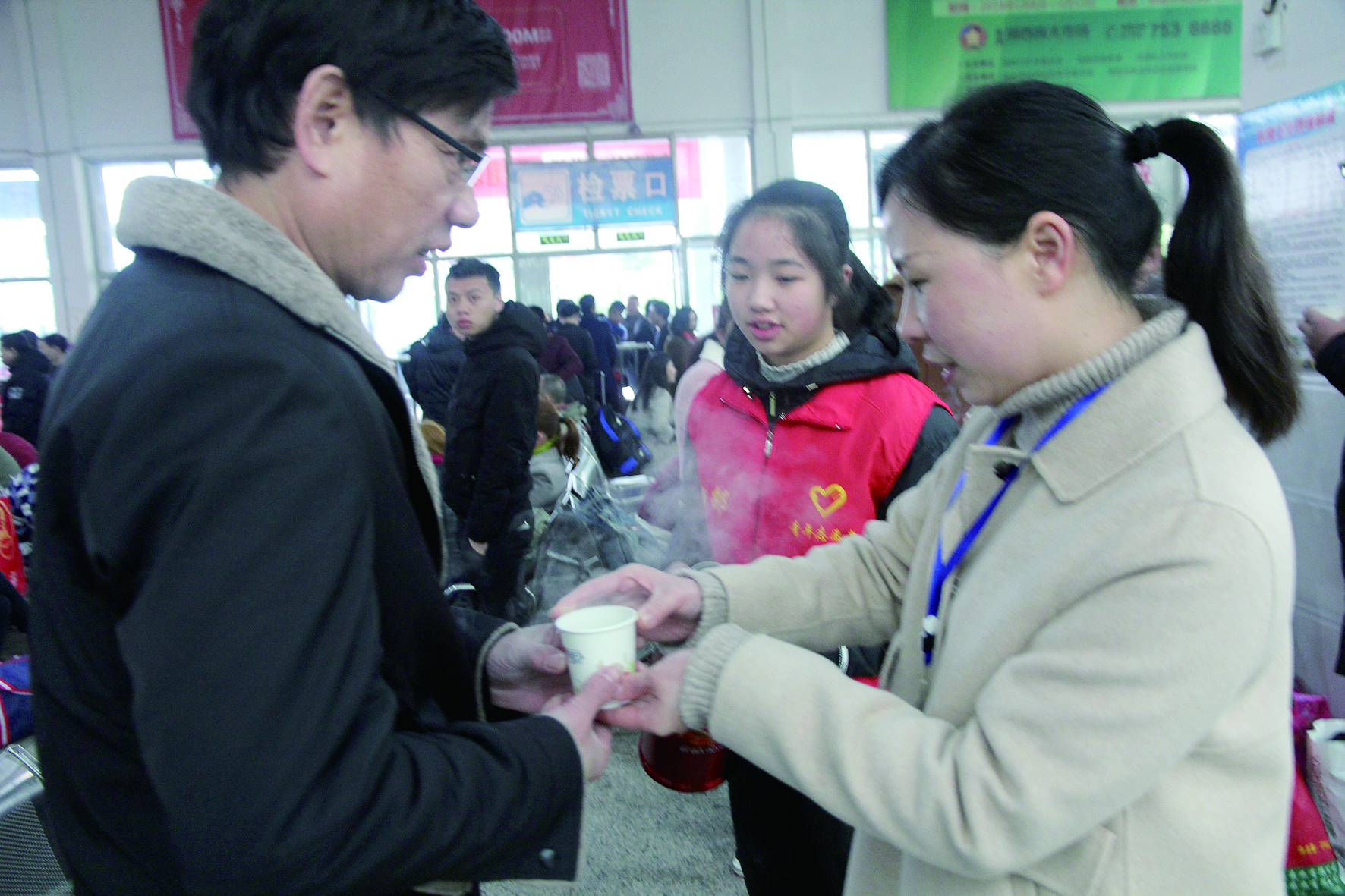 母女服務(wù)春運(yùn) 2月13日，記者在新邵分公司汽車站看到，該分公司安全科副科長李喜梅與其在新邵一中初中部1701班就讀女兒劉嘉怡在車站擔(dān)當(dāng)志愿者。李喜梅在候車室耐心為旅客釋疑解惑，劉嘉怡為旅客遞上一杯杯熱茶，有時(shí)母女也相互合作，其樂融融。 祖冠 攝影報(bào)道